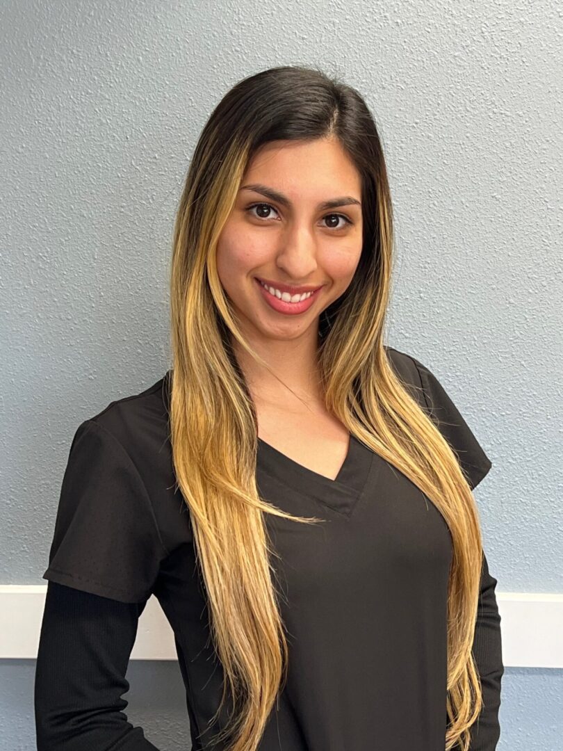 A woman with long hair standing in front of a wall.