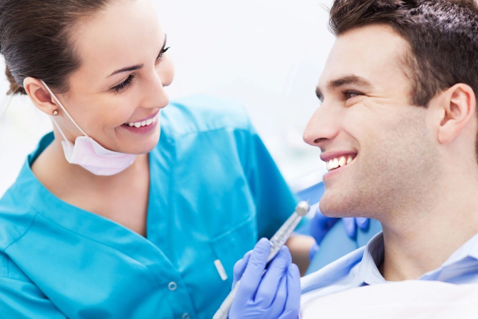 A dentist and his assistant are smiling at each other.